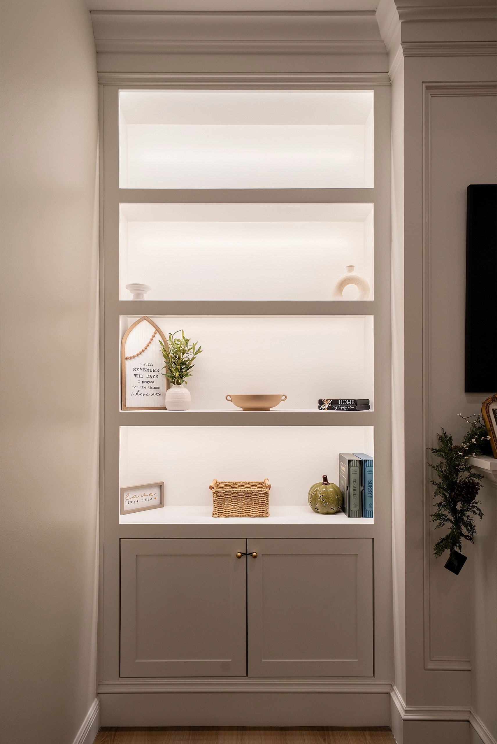 Custom built-in white shelving unit featuring integrated recessed LED lighting and shaker-style lower cabinets.
